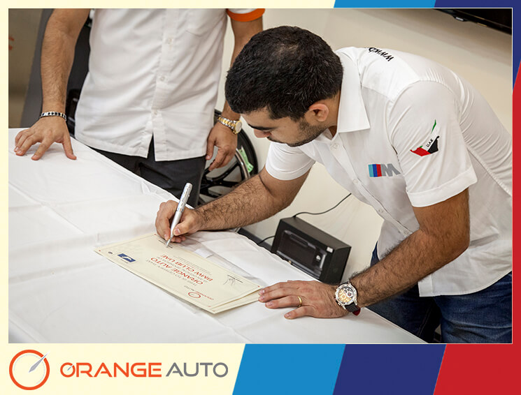A BMW club man signing a certificate at Orange Auto center