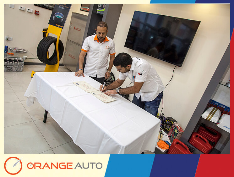 A man signing a certificate at Orange Auto center Dubai