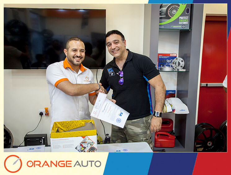 Workers giving a certificate at Orange Auto center