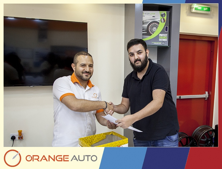 Workers issuing a certificate at Orange Auto center